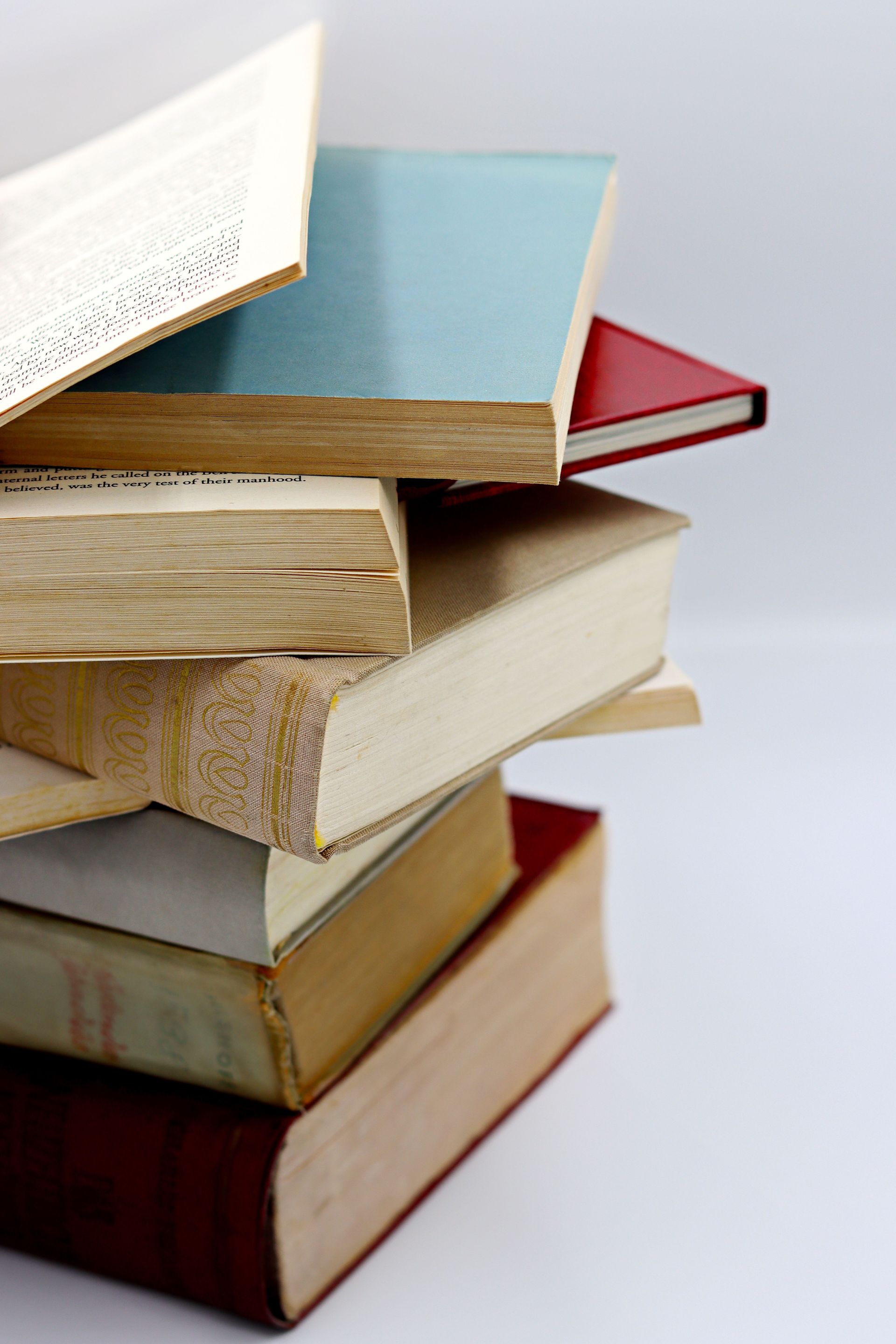 A vertical stack of various hardcover books with visible pages, ideal for literature themes.